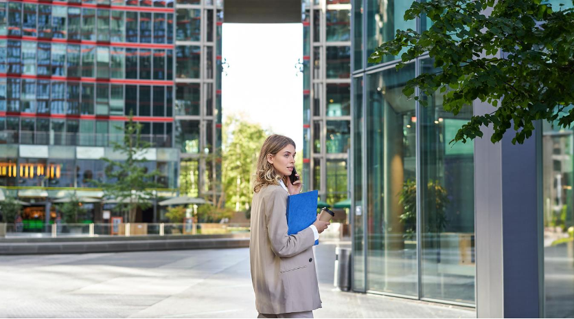 Investisseuse consultant des documents devant un immeuble tertiaire moderne en Europe