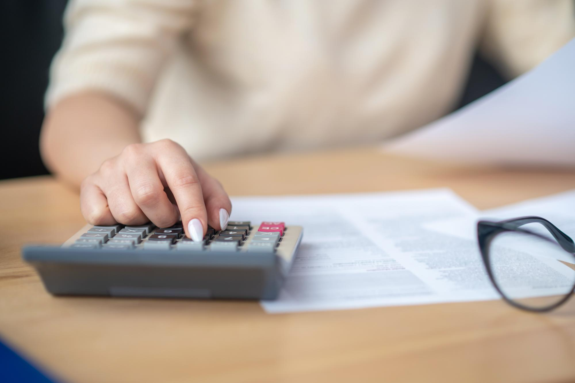 Personne utilisant une calculatrice pour analyser l’impact des prélèvements sociaux sur les revenus de SCPI.