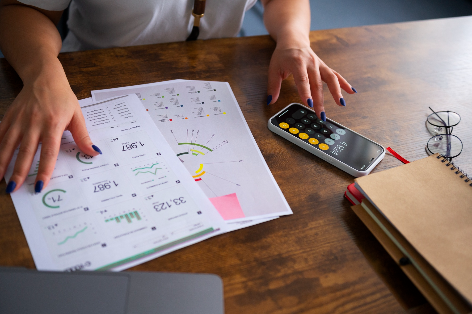 Personne consultant des documents financiers avec une calculatrice pour analyser la valeur de reconstitution d’une SCPI.